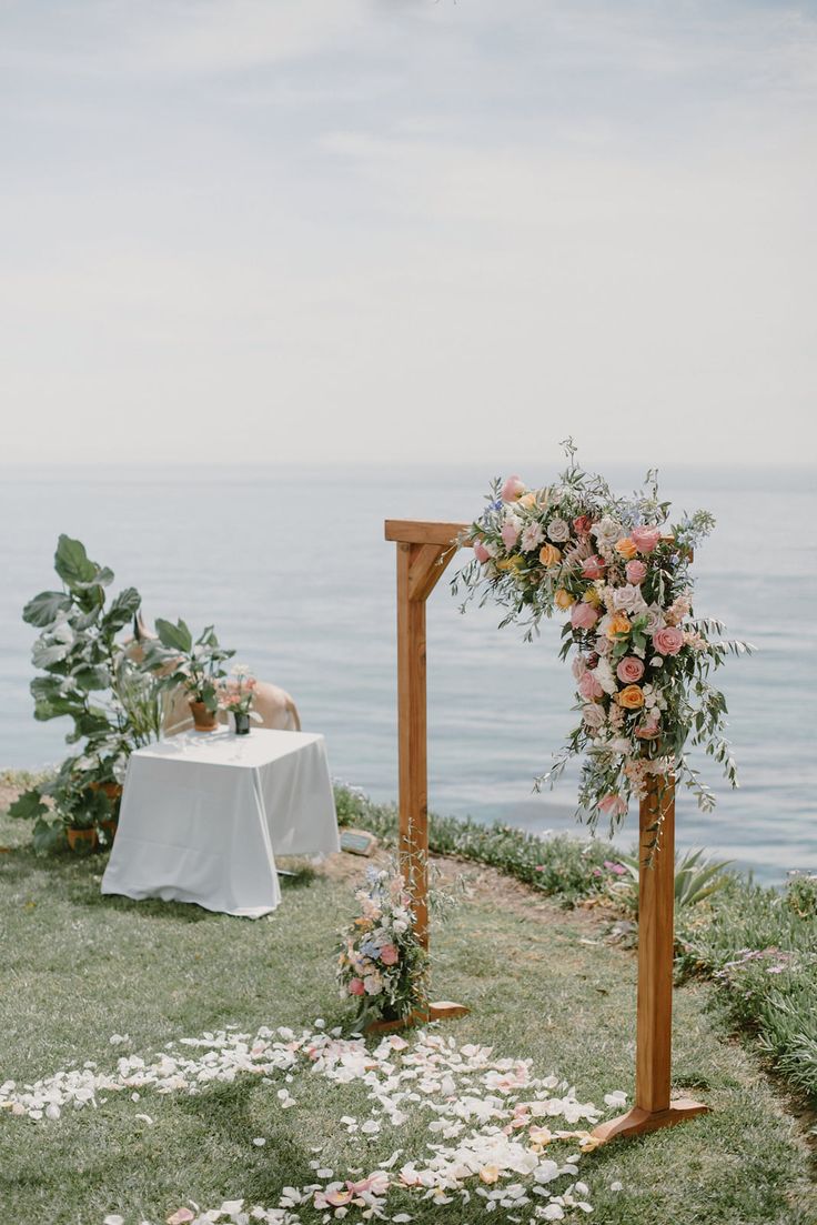 an outdoor ceremony setup with flowers and greenery on the grass by the water,