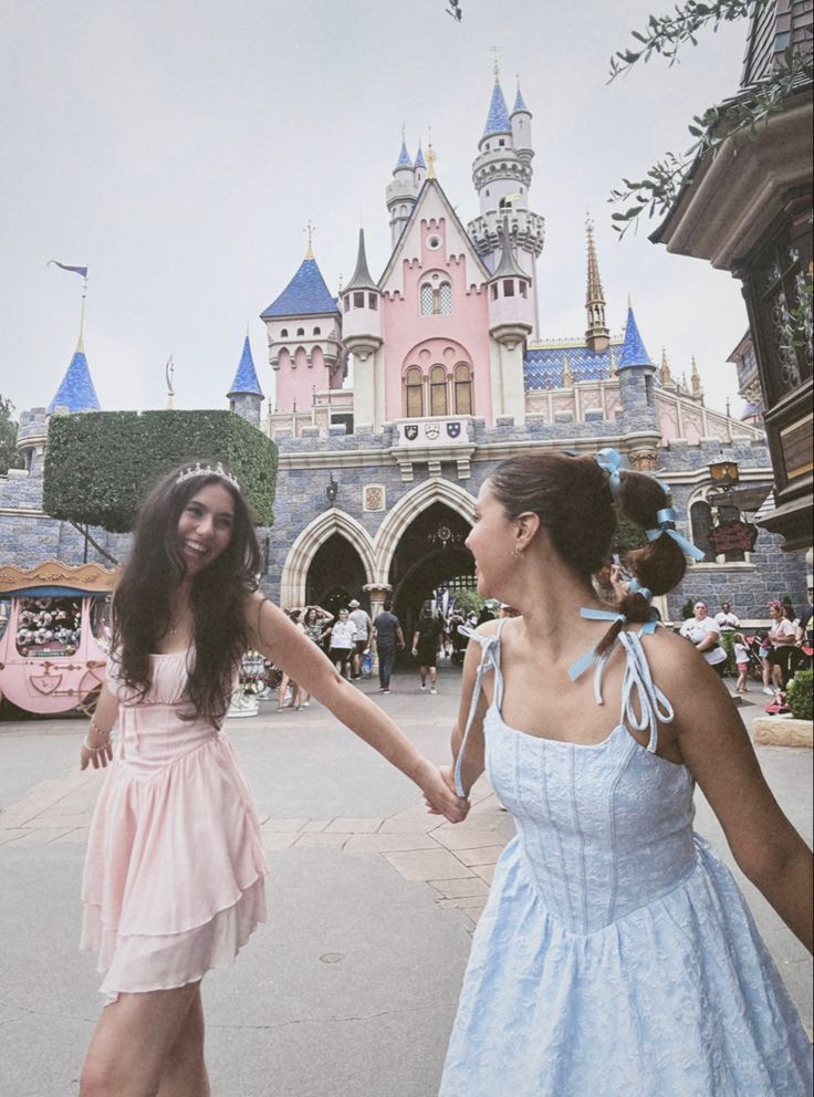 two girls are holding hands in front of a castle