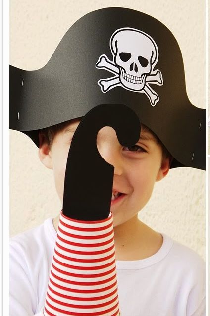 a young boy wearing a pirate hat and holding up a finger