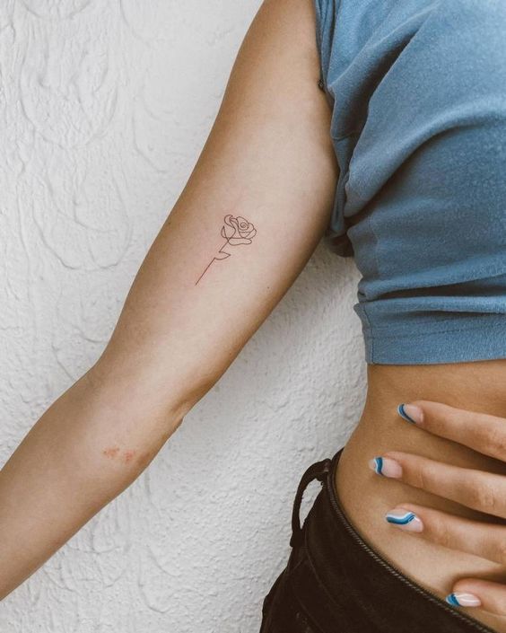 a woman's stomach with a small rose tattoo on her left ribcage