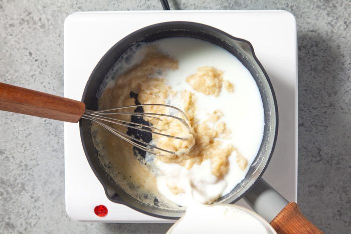 a pan filled with food on top of a stove next to a whisk