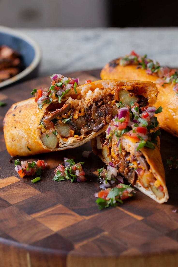 the burritos have been cut in half and are on a wooden cutting board