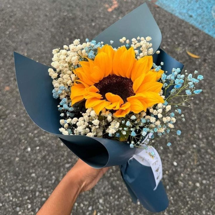 a bouquet of sunflowers and baby's breath is being held by someone