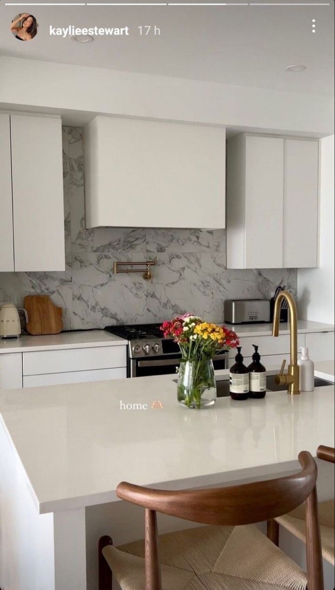 a white kitchen with marble counter tops and wooden stools in front of the sink