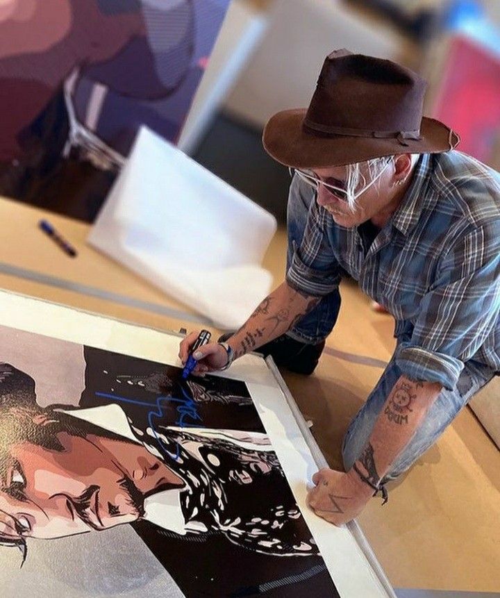 a man in a hat and plaid shirt is working on an art piece