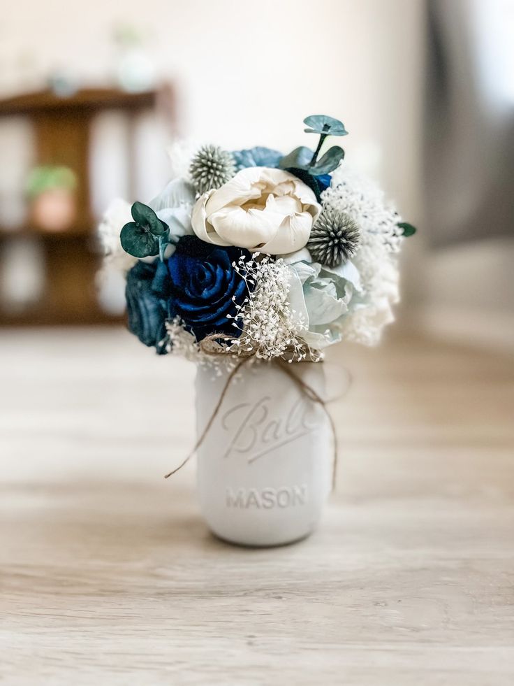 a white vase filled with flowers on top of a wooden table