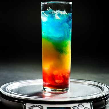 a multicolored drink sitting on top of a scale with water in the middle