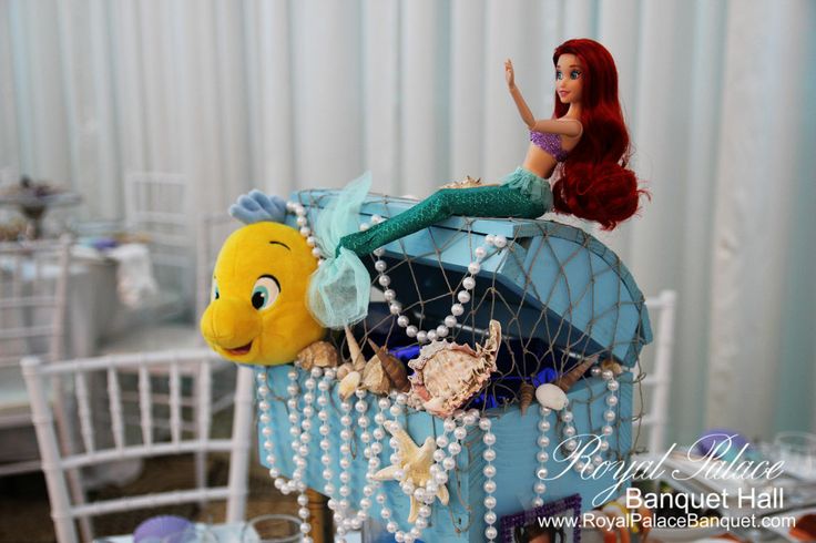 a mermaid doll sitting on top of a baby carriage with other toys in it's back