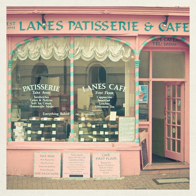 a pink store front with lots of signs on the window and windows that read lanes, patisserie & cafe