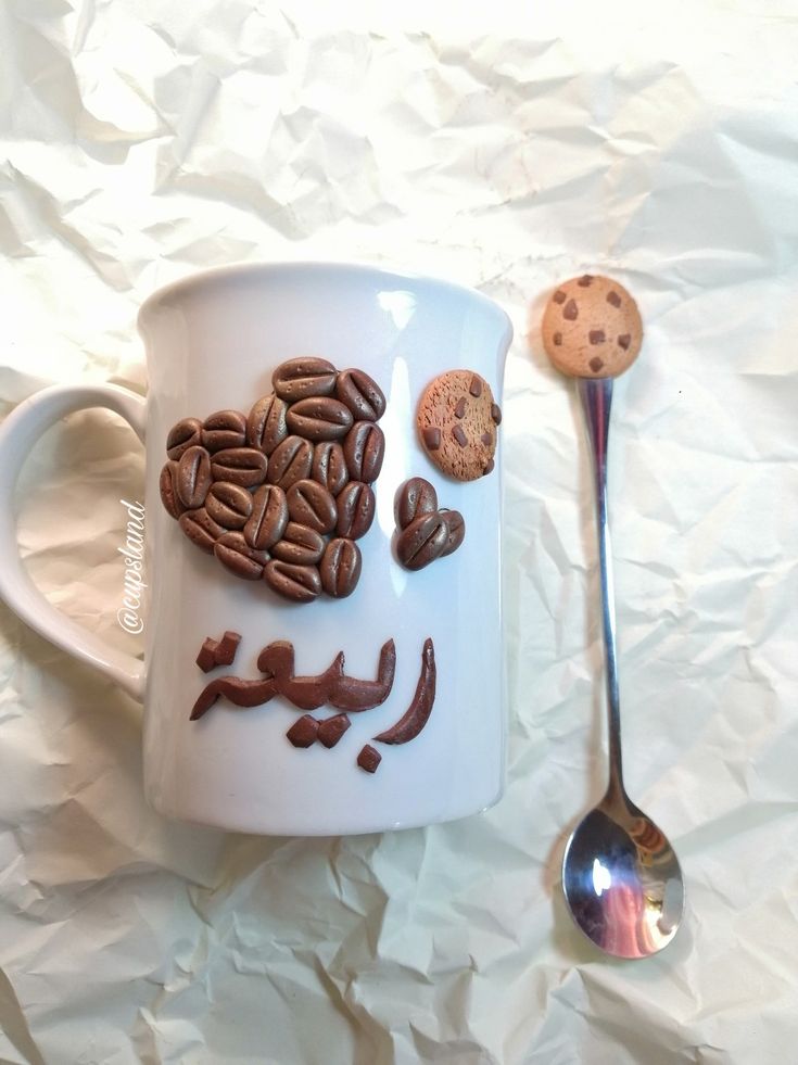 a coffee cup with chocolate chips and cookies on it next to a spoon