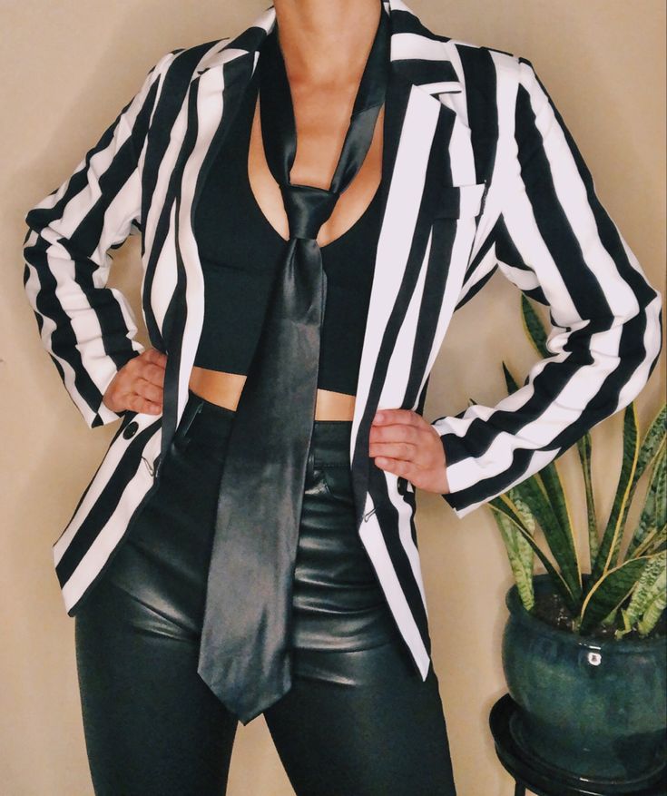 a woman in black and white striped jacket posing for the camera with her hands on her hips