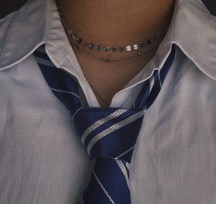 a man wearing a black and white striped tie with a silver bead necklace on his neck