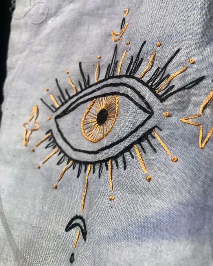 an eye embroidered onto a shirt with gold thread