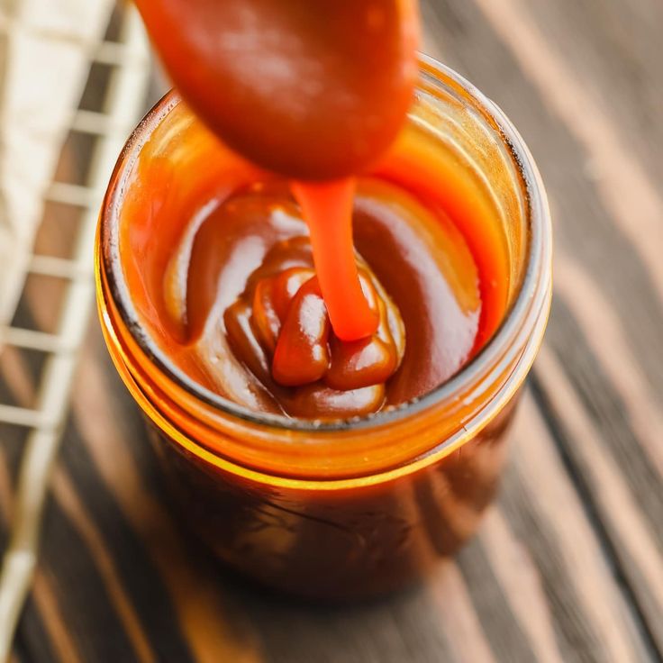 an orange jar filled with sauce sitting on top of a wooden table