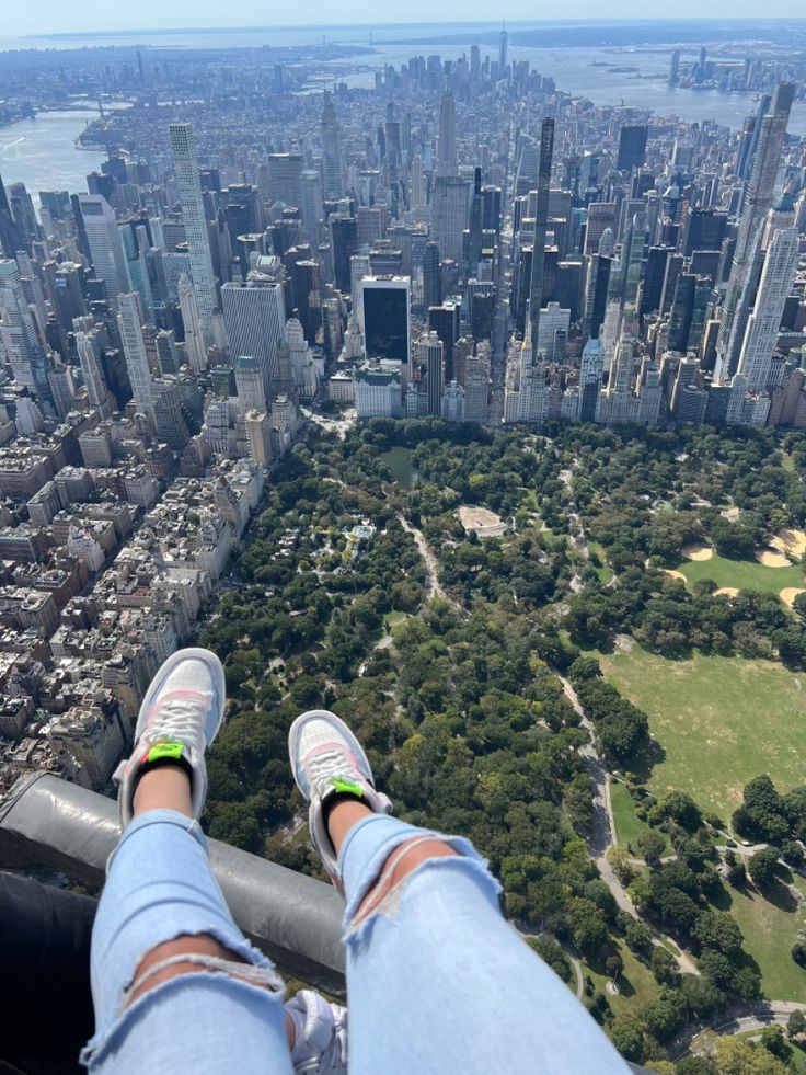 a person standing on the edge of a tall building with their feet in the air