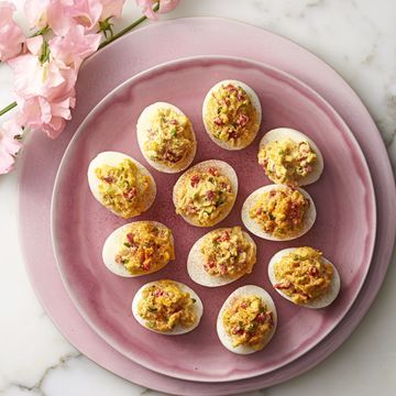 small deviled eggs on a pink plate with flowers in the backgroung