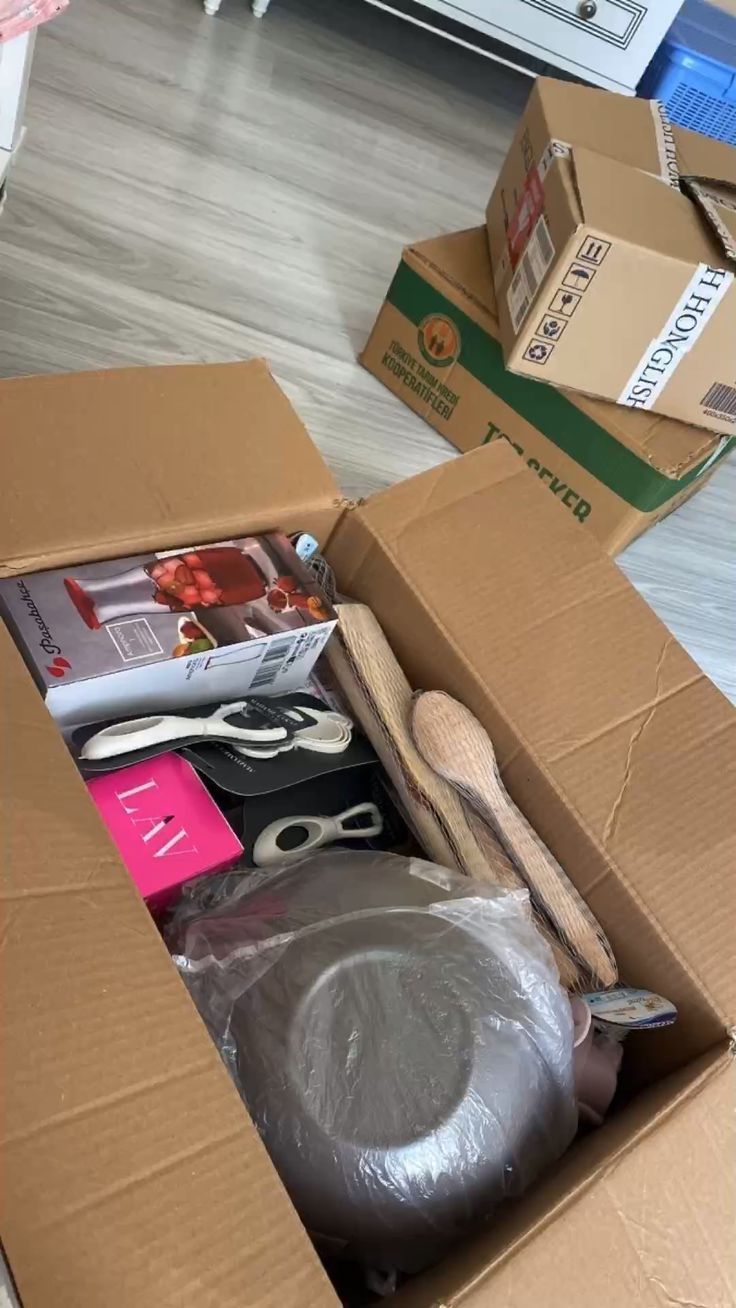 an open box with scissors and other items in it on the floor next to boxes