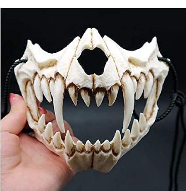 a person is holding up a fake animal's teeth