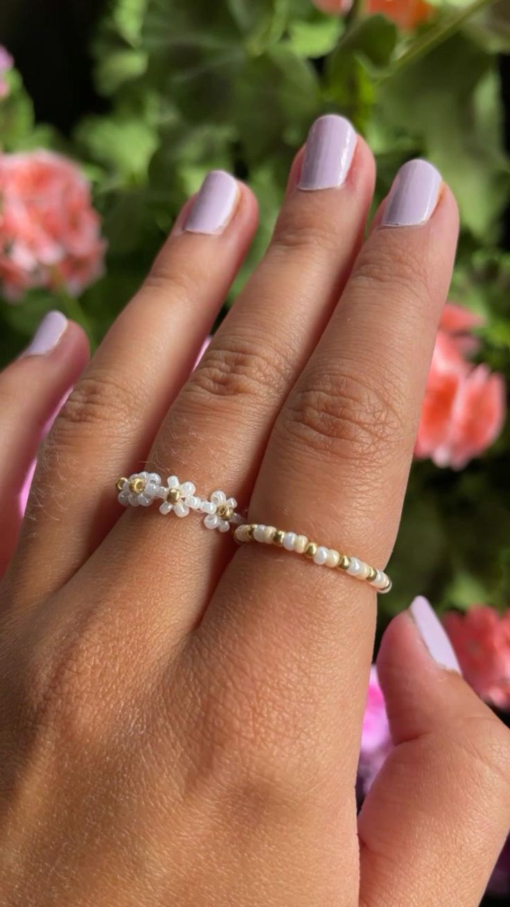 a woman's hand wearing a gold ring with pearls