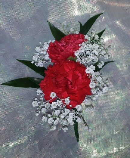 two red carnations and white baby's breath in a bouquet on a silver background