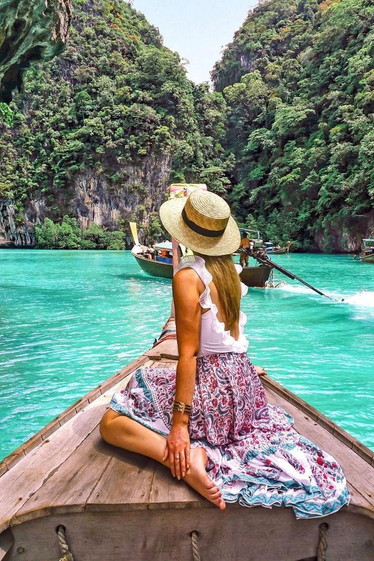 a woman in a hat is sitting on the back of a boat looking out into the water