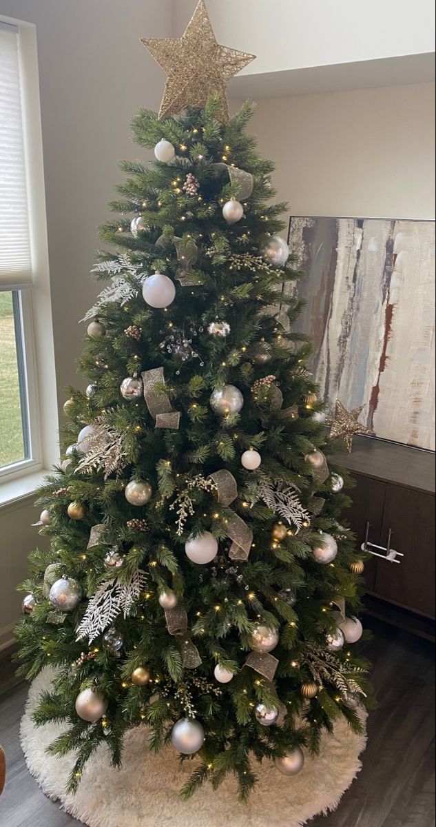 a decorated christmas tree in the corner of a room with a large window behind it