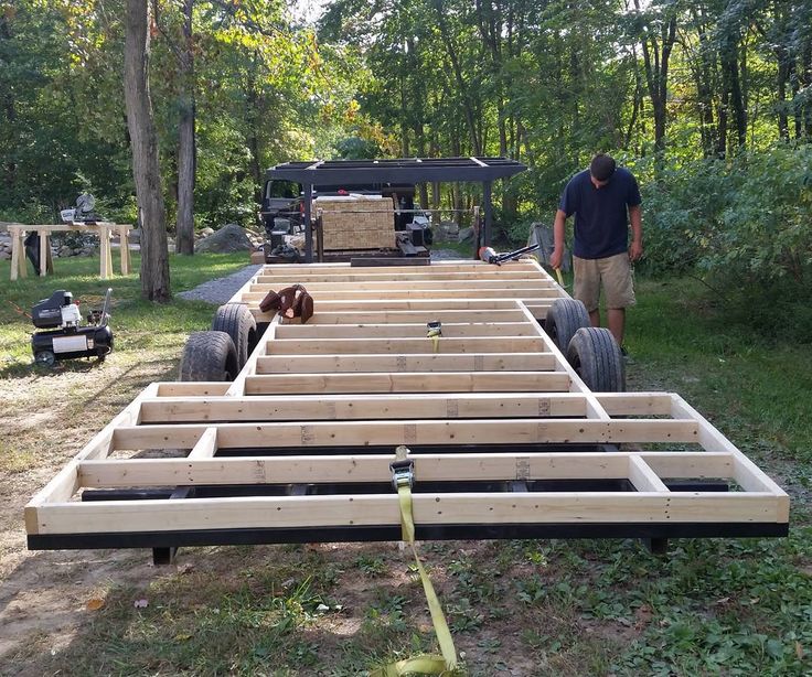 a man standing next to a truck in the middle of a forest filled with lots of wood