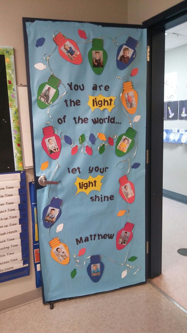 a bulletin board with pictures and words on it in an office cubicle, next to a door that says you are the light of the world let your light shine