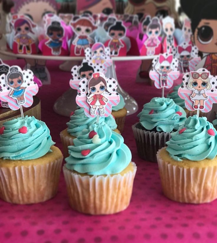 cupcakes with blue frosting and decorations on them are sitting on a table