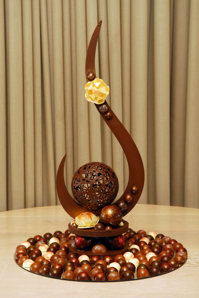 a sculpture made out of chocolates and nuts on a table with curtains in the background