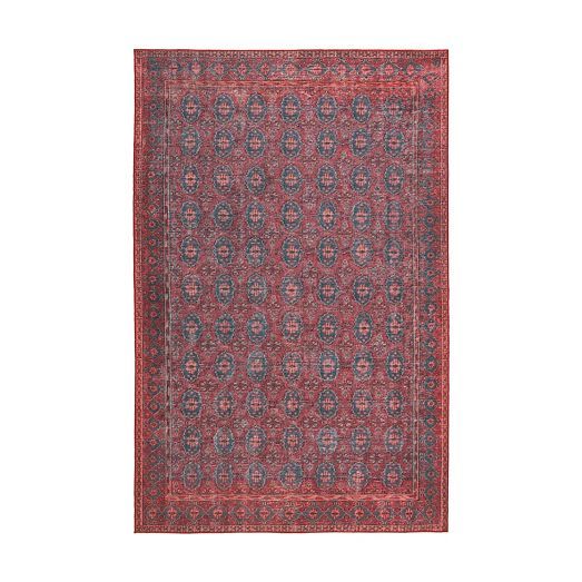 an antique persian rug with red and blue designs on the center, in front of a white background