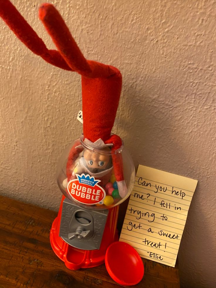 an elf's hat on top of a gummy machine with a note attached to it