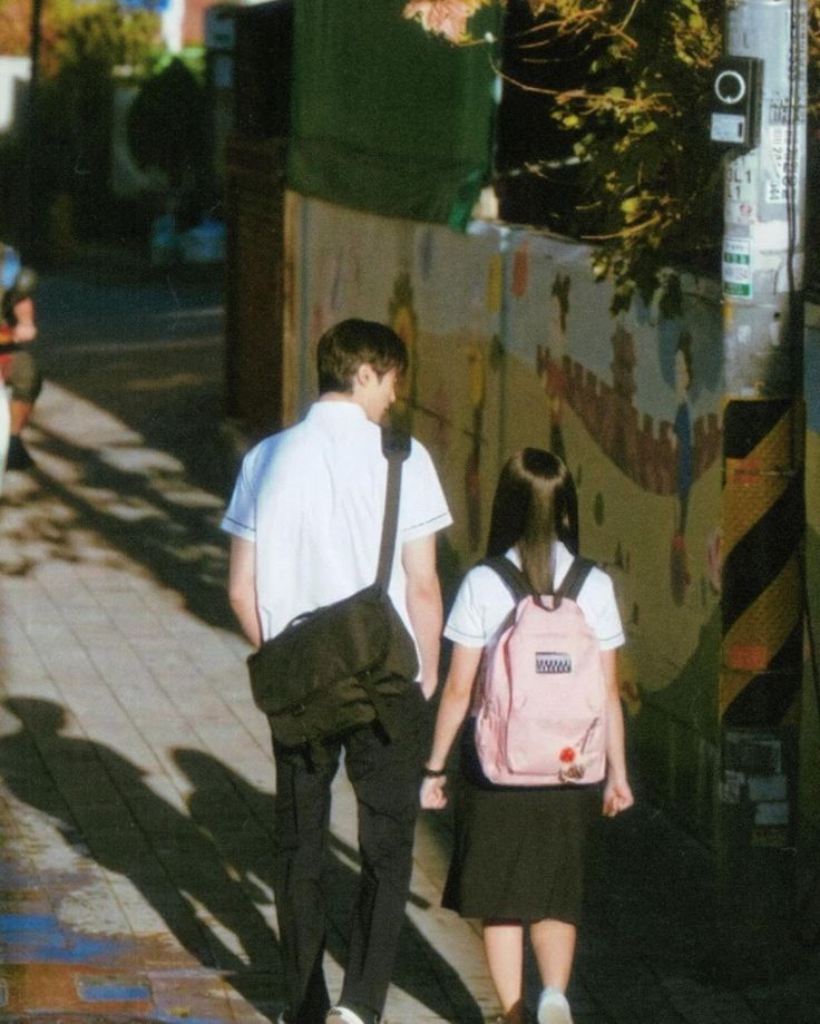 two people walking down the street with backpacks on