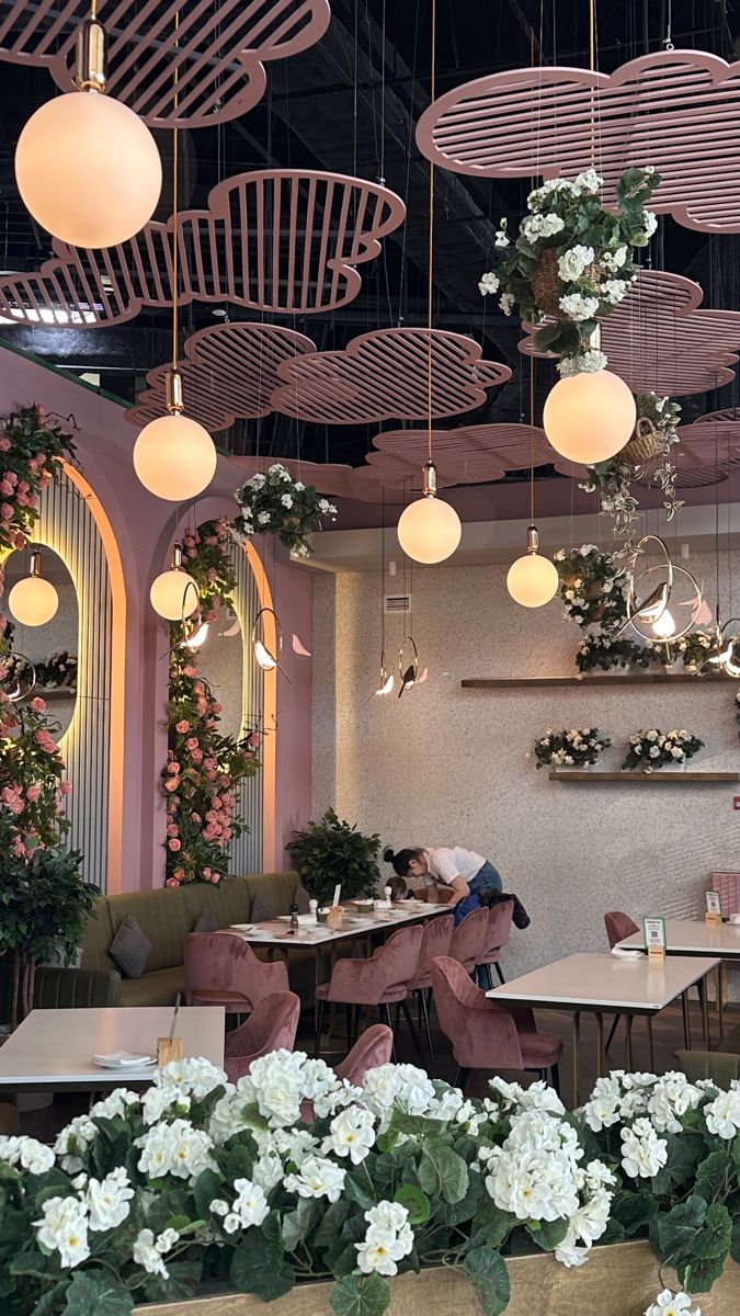 the interior of a restaurant with tables and flowers in baskets on the ceiling, along with hanging lights