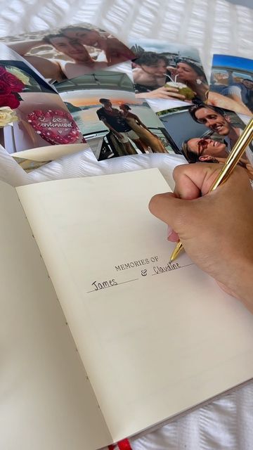 a person is writing in a notebook with pictures on the bed behind them and a pen