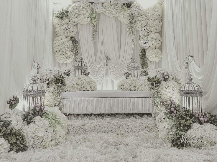 a white wedding ceremony setup with flowers and birdcages