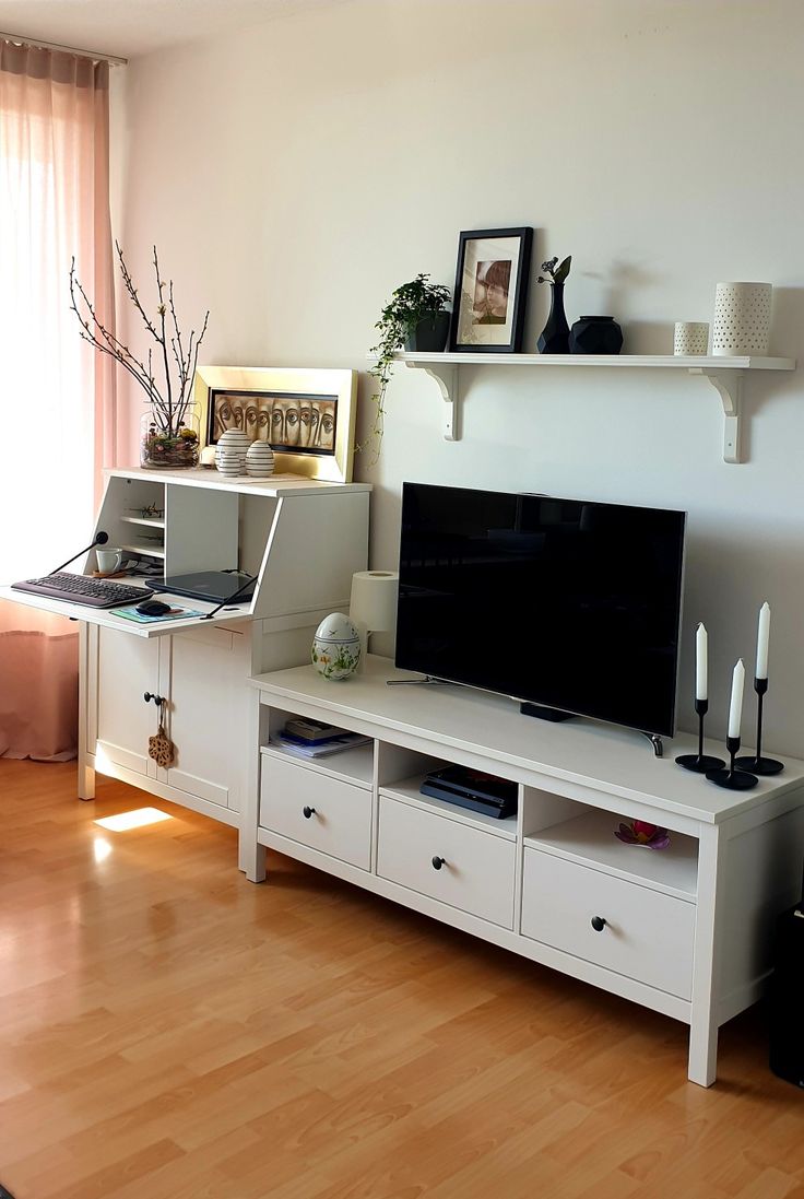 a flat screen tv sitting on top of a white entertainment center next to a window