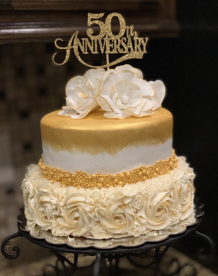 a 50th anniversary cake decorated with white and gold flowers