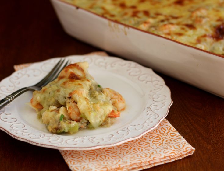 a white plate topped with food next to a casserole dish on top of a wooden table