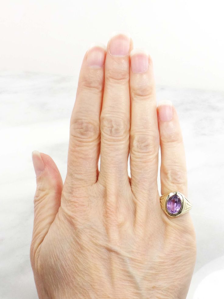 This Vintage 14k Amethyst Ring has clean, elegant lines for a classic look. The setting is 14k yellow gold and showcases a medium tone amethyst stone. The setting has wonderful Art Deco style at the shoulders. The amethyst measures approximately 7.2 x 9.8 x 5.85 mm or approximately 2.2 carats by measurement. The ring is circa the 1930's and under magnification some scratches and abrasions are visible on the stone commensurate with wear. However, this would not be noticeable when the ring is worn Purple Ruby Ring For Formal Occasions, Oval Amethyst Signet Ring For Formal Occasions, Timeless 14k Gold Amethyst Ring For Anniversary, Fine Jewelry Oval Amethyst Ring In 14k Gold, Classic 14k Gold Amethyst Birthstone Ring, Classic Purple Amethyst Ring With Polished Finish, Formal Purple Oval Ruby Ring, Oval Amethyst Ring With Accent Stones In 14k Gold, 14k Gold Oval Amethyst Ring With Accent Stones