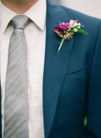 a man wearing a suit and tie with a boutonniere on his lapel