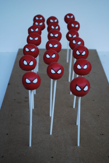 red and white cake pops with spiderman faces on them