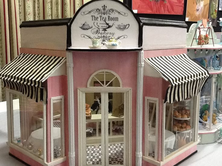 the doll house is pink and white with striped awnings