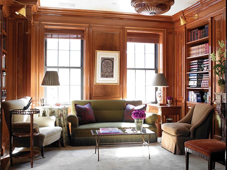 a living room filled with lots of furniture and bookshelves next to two windows