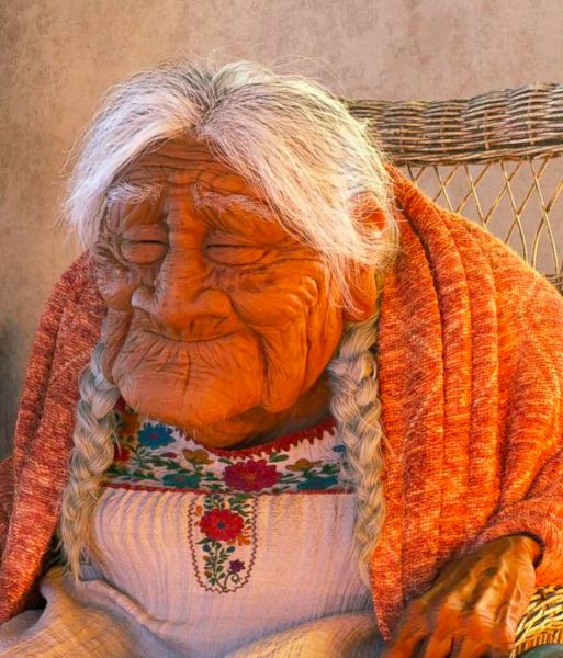 an old woman with braids sitting in a chair