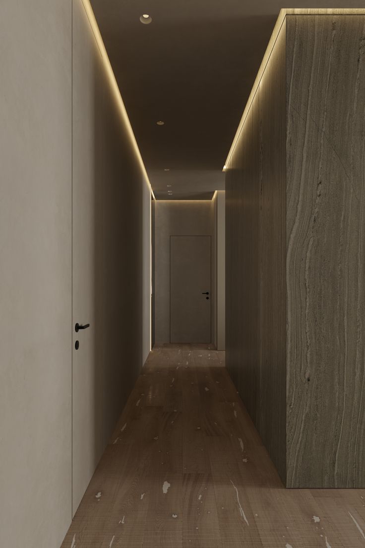 an empty hallway with wood flooring and lighting on either side of the room is lit by recessed lights