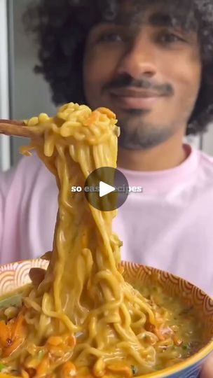 a man holding a bowl of noodles with chopsticks