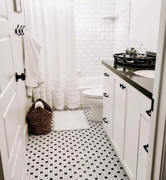 a white bathroom with black and white floor tiles