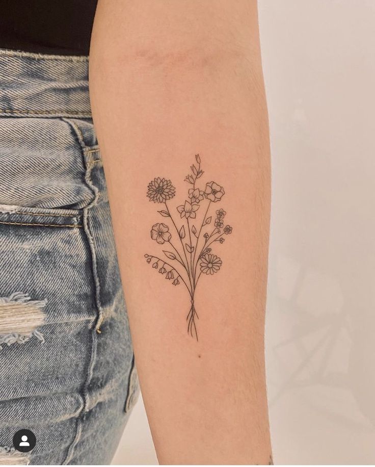 a woman's arm with a small flower tattoo on the left side of her arm