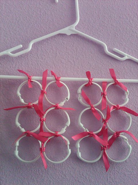 four pairs of scissors hanging on a hanger with pink ribbon attached to the handles